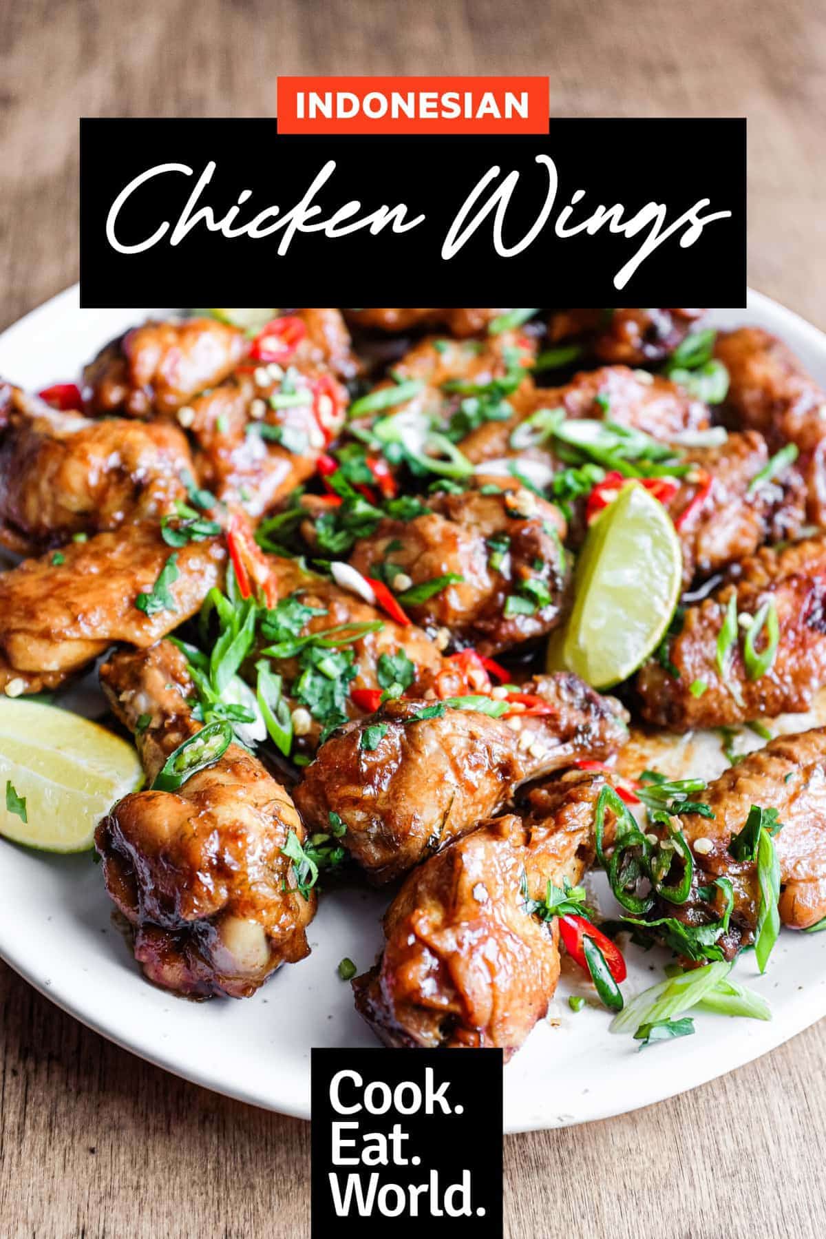 A platter of Indonesian chicken wings garnished with cilantro, chillies and spring onion alongside some lime wedges.