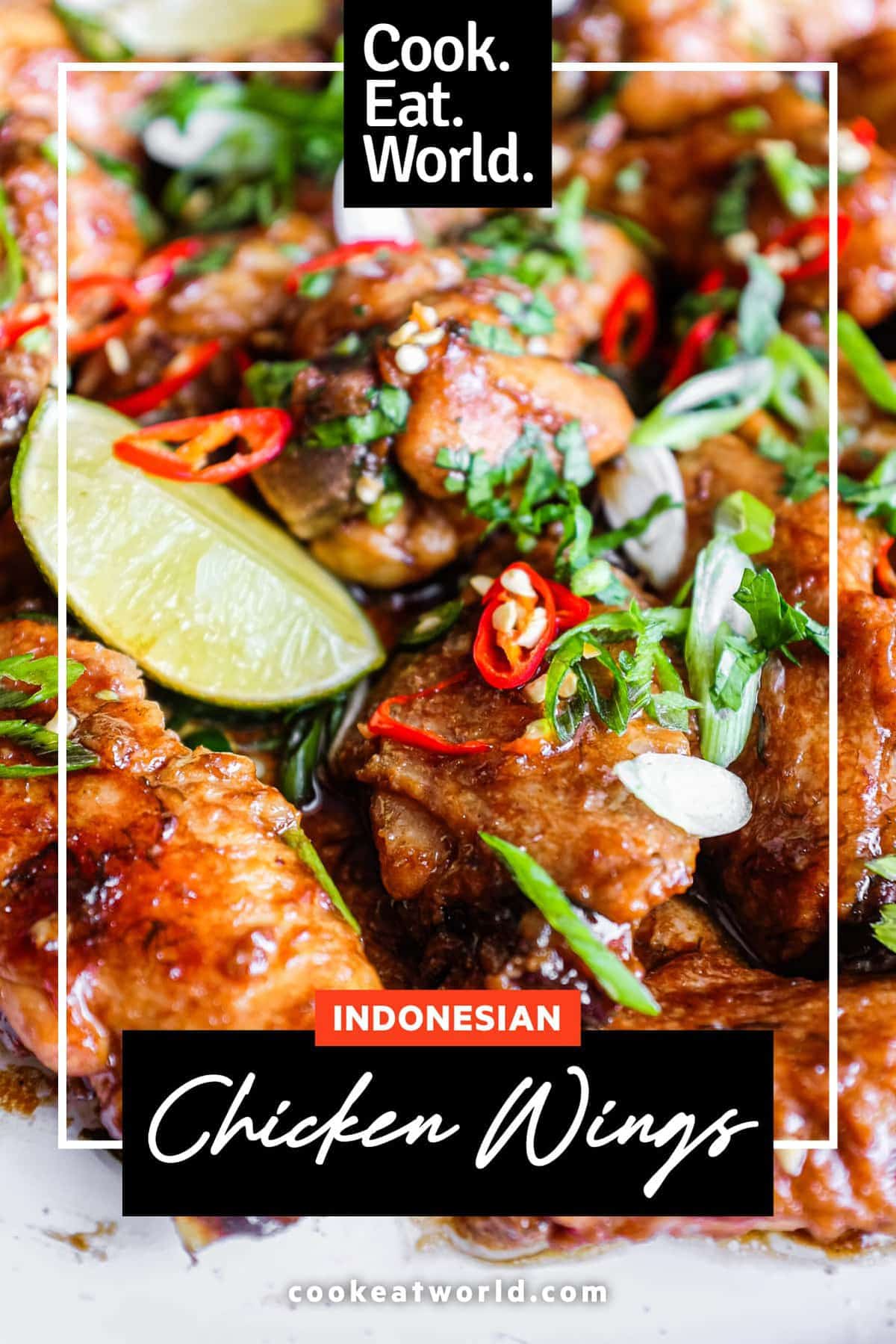 A platter of Indonesian chicken wings garnished with cilantro, chillies and spring onion alongside some lime wedges.