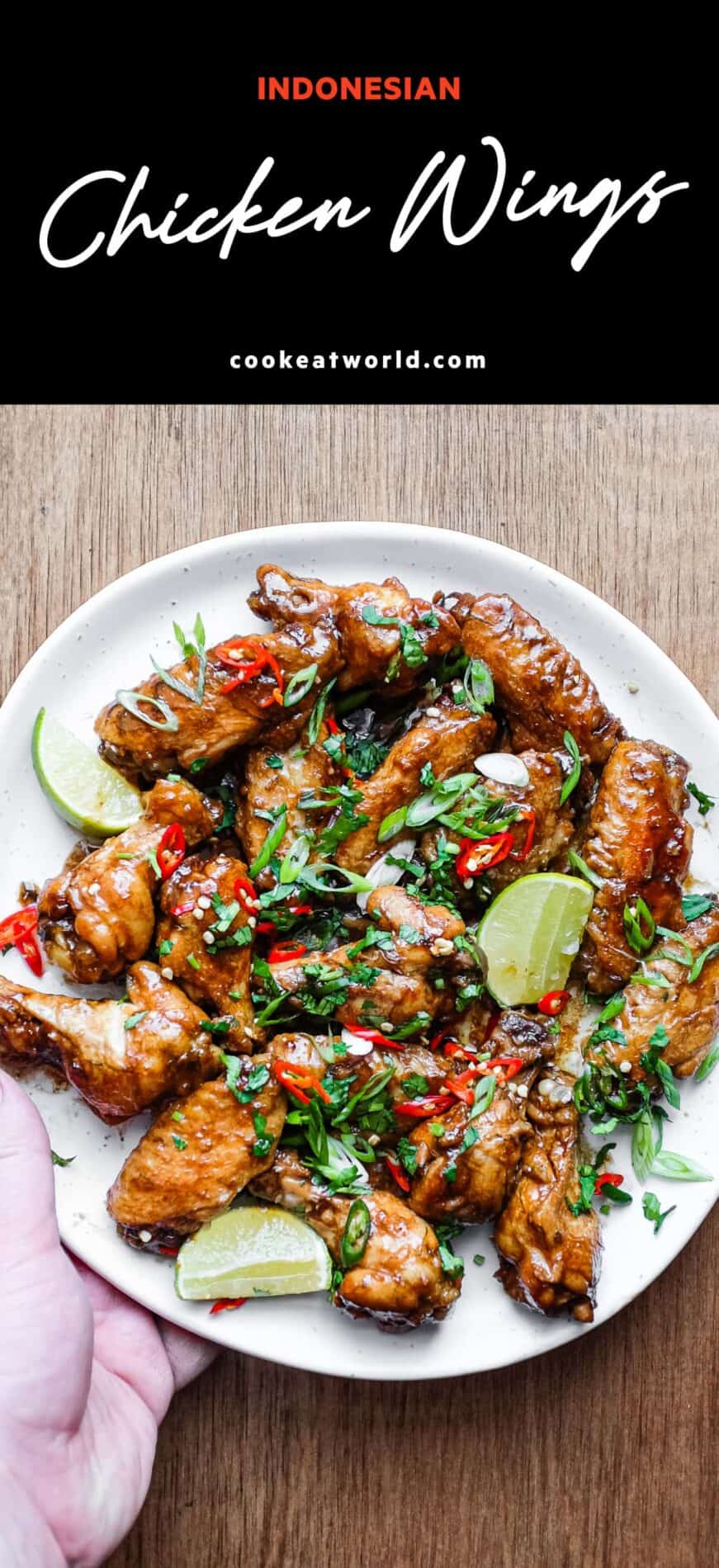 A platter of Indonesian chicken wings garnished with cilantro, chillies and spring onion alongside some lime wedges.