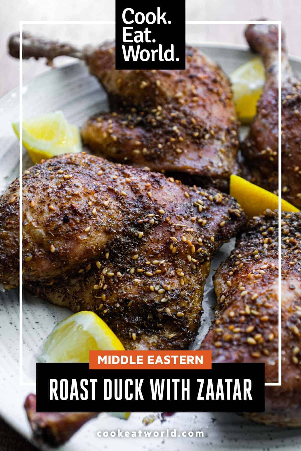 4 roasted duck legs with zaatar on a serving plate with small lemon wedges