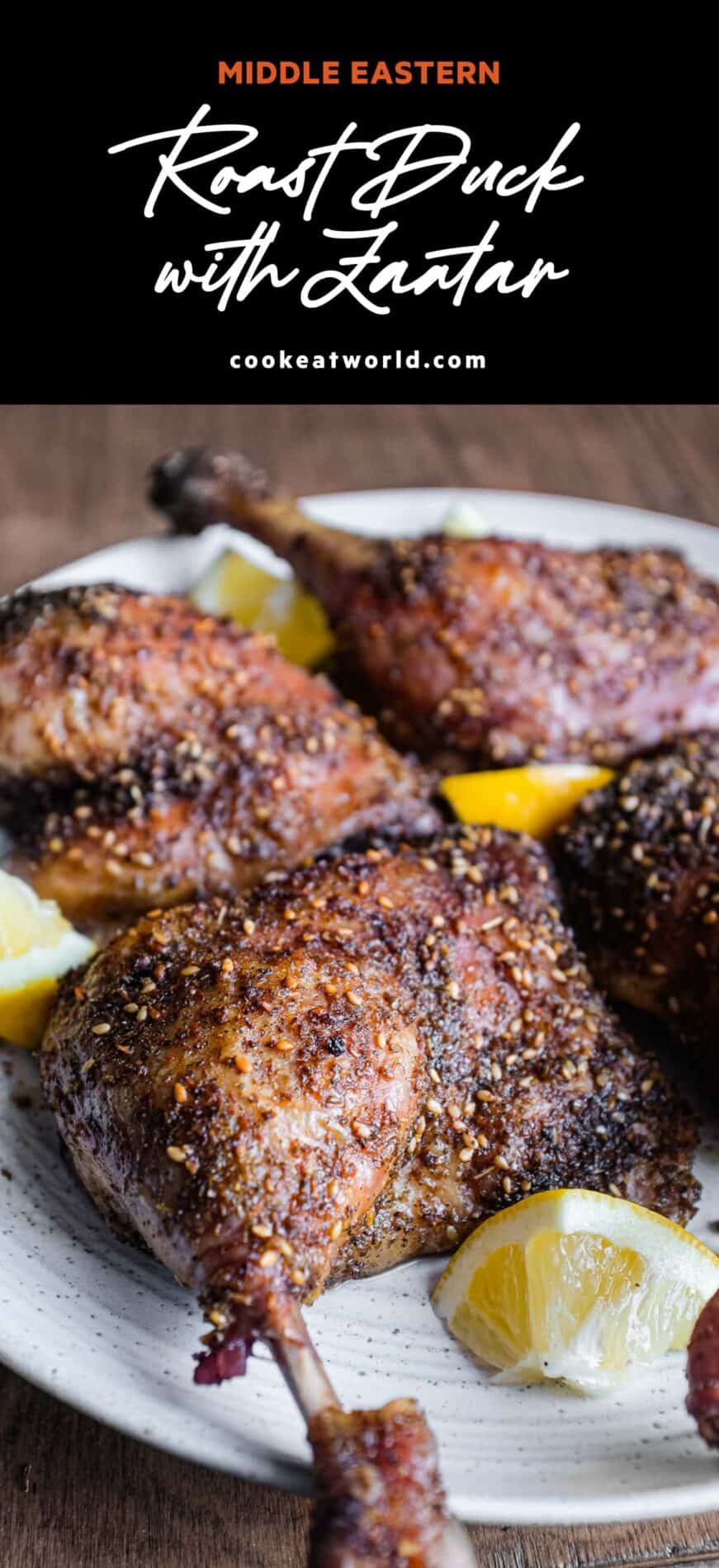 4 roasted duck legs with zaatar on a serving plate with small lemon wedges