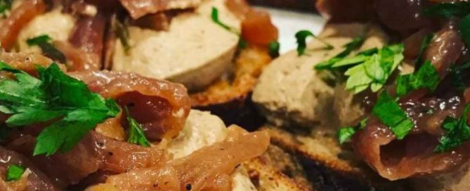 Rabbit liver pate spread on sourdough toast. Topped with caramelised onions and fresh parsley