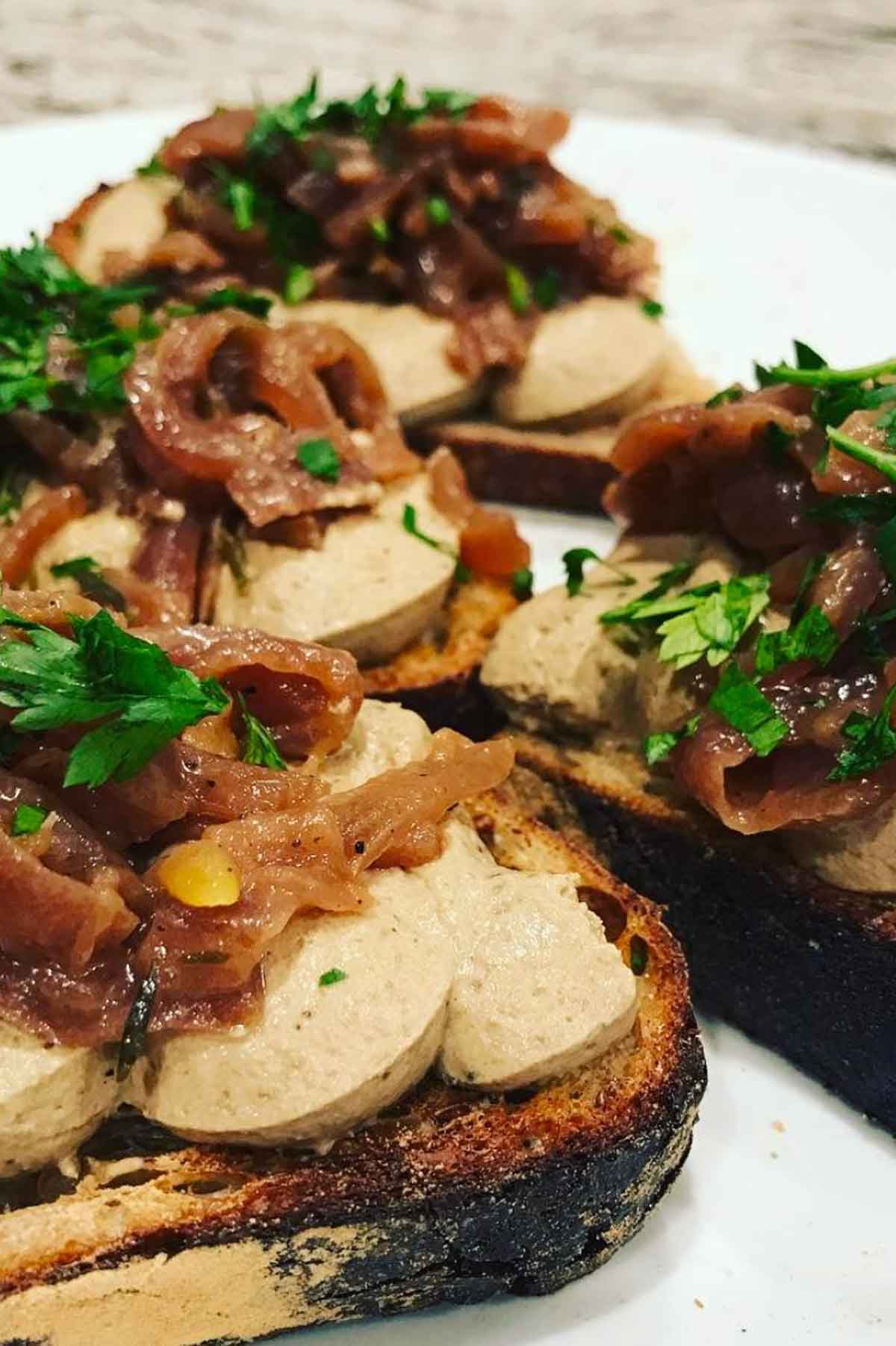 Rabbit liver pate spread on sourdough toast. Topped with caramelised onions and fresh parsley