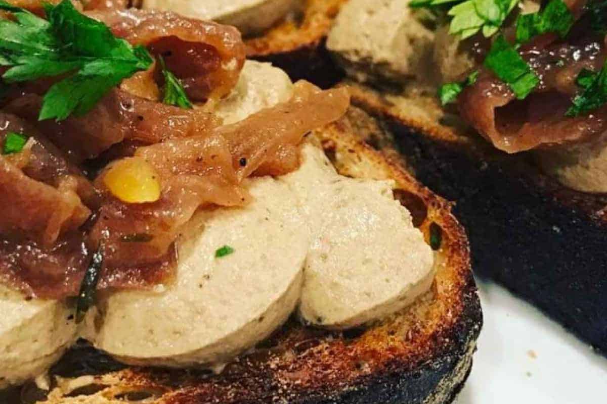 Rabbit liver pate spread on sourdough toast. Topped with caramelised onions and fresh parsley