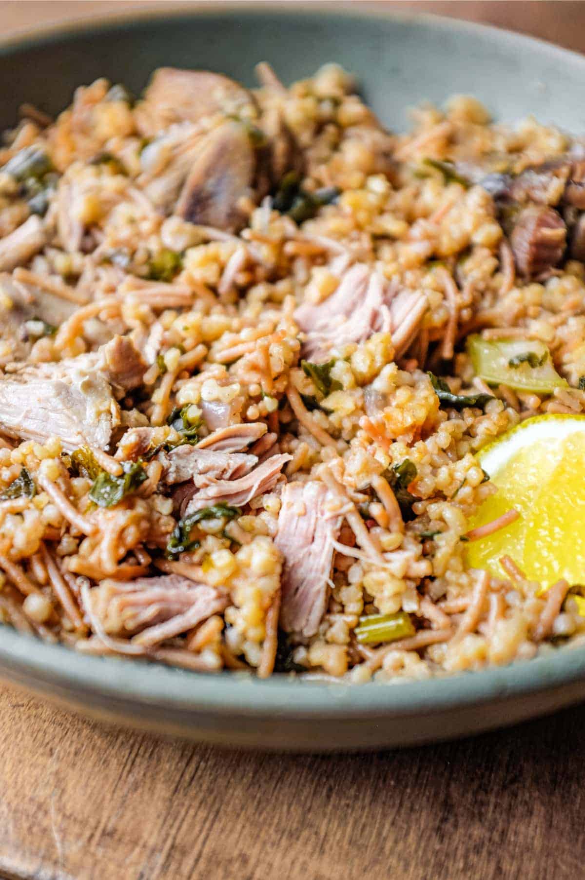 A bowl of Turkish bulgur pilav with a fork and a wedge of lemon.