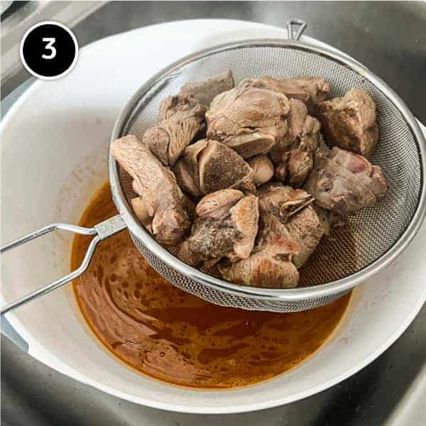 the lamb is drained in a sieve over a large bowl to retain the cooking liquid