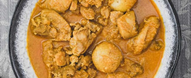 A bowl of Malaysian Chicken Kapitan Curry (Kari Kapitan) with rice and salad.