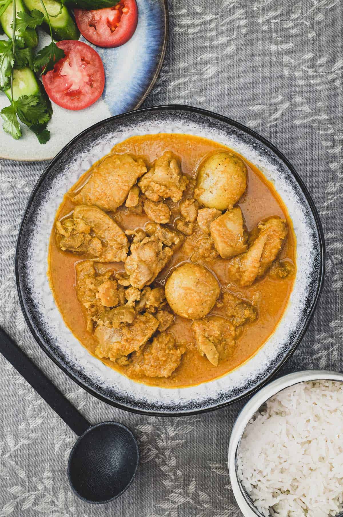 A bowl of Malaysian Chicken Kapitan Curry (Kari Kapitan) with rice and salad.