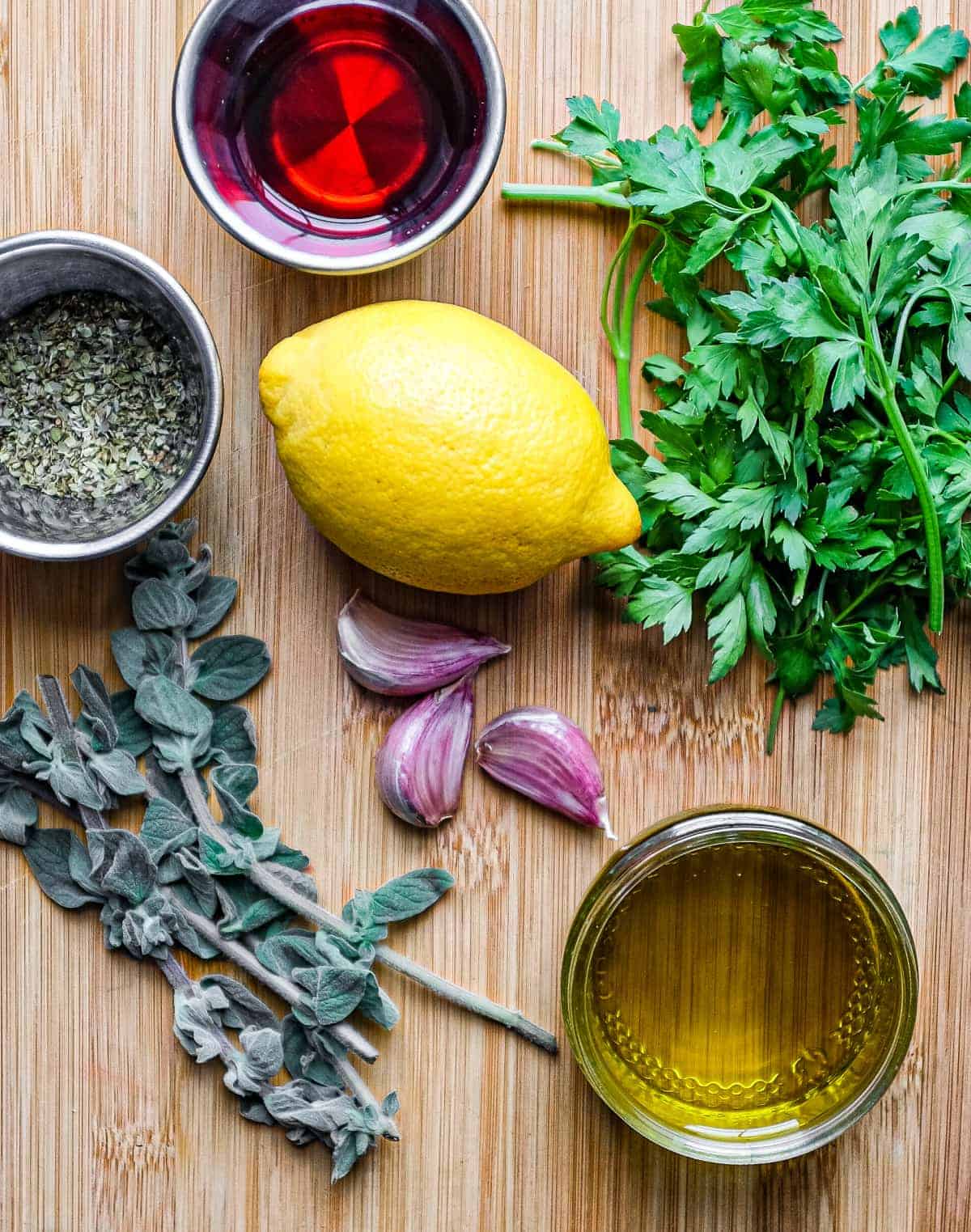 The ingredients for chimichurri sauce, including lemon, parsley, oregano, red wine vinegar, garlic and olive oil.