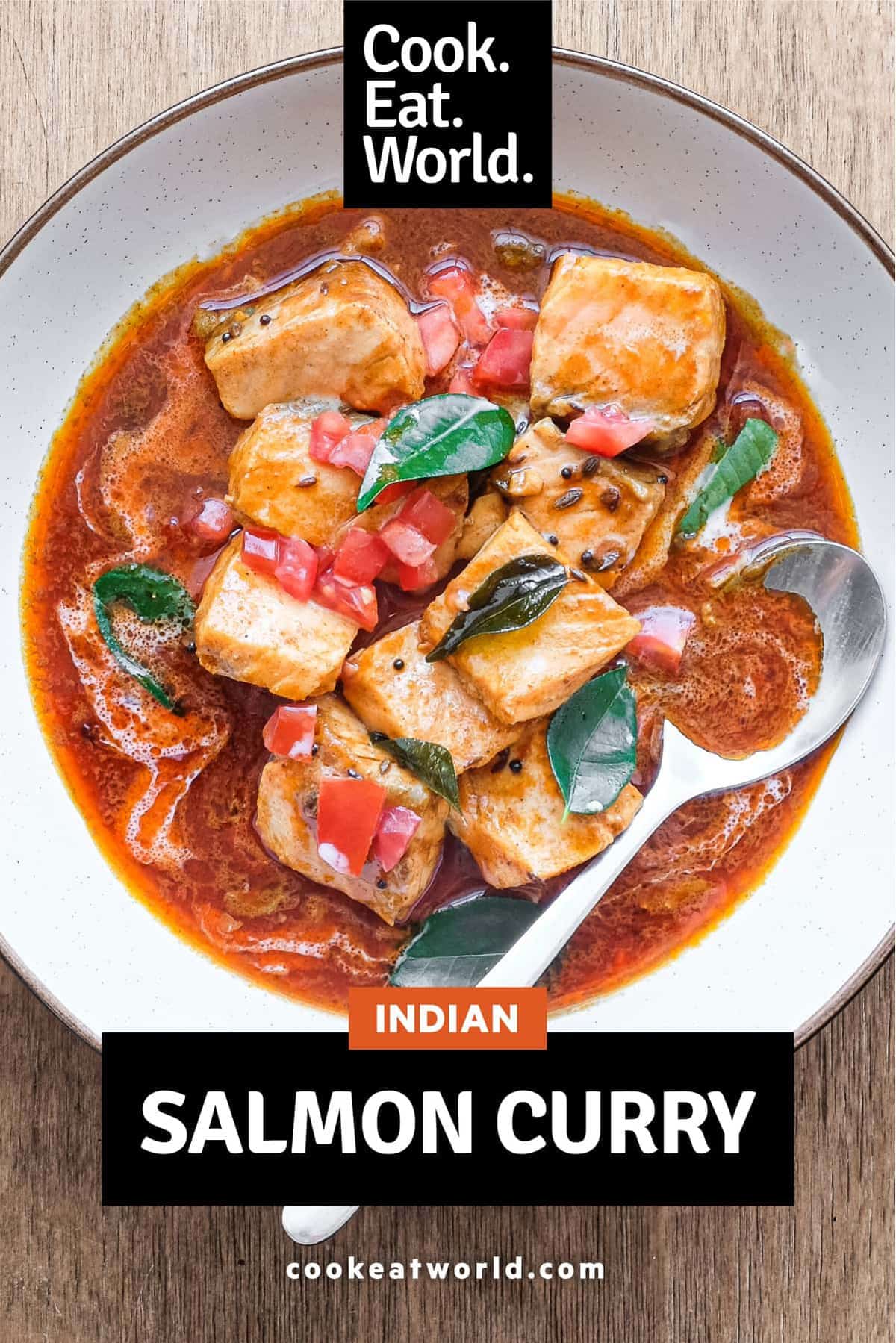 A bowl of Indian Salmon Curry decorated with fresh curry leaves, tomato and a drizzle of coconut cream