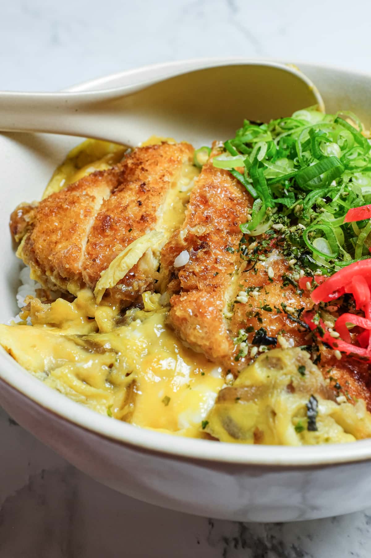Homemade chicken katsudon with sliced katsu resting on onions and rice