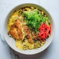Chicken katsudon served in a deep bowl with soft-set egg and savoury dashi sauce