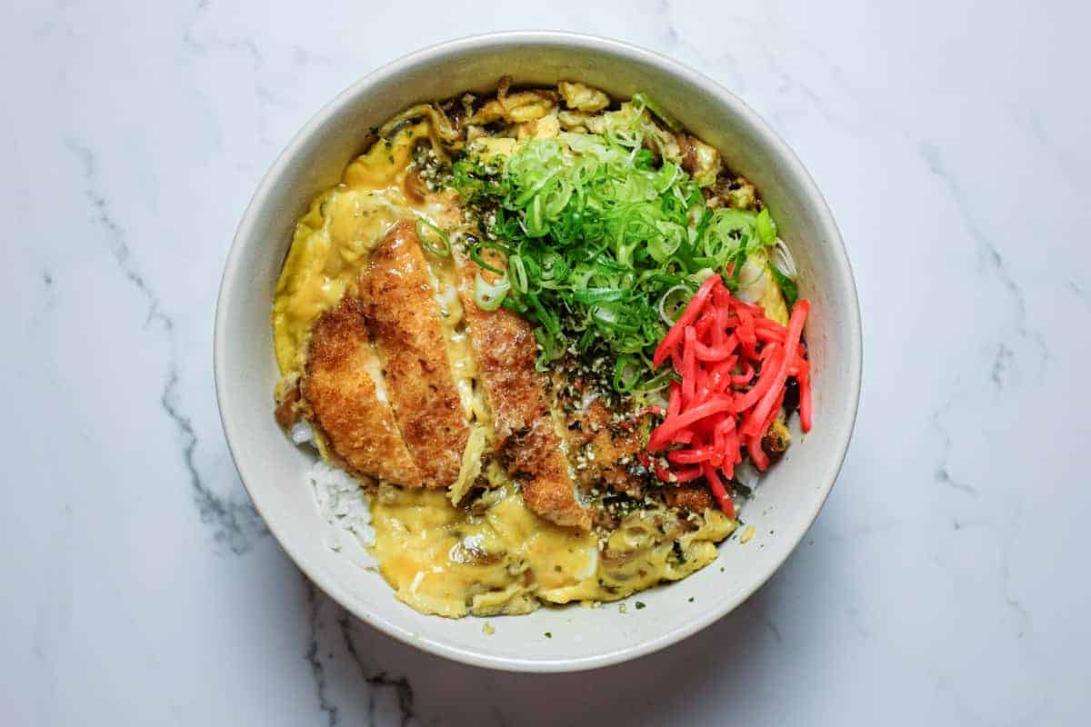 Chicken katsudon served in a deep bowl with soft-set egg and savoury dashi sauce