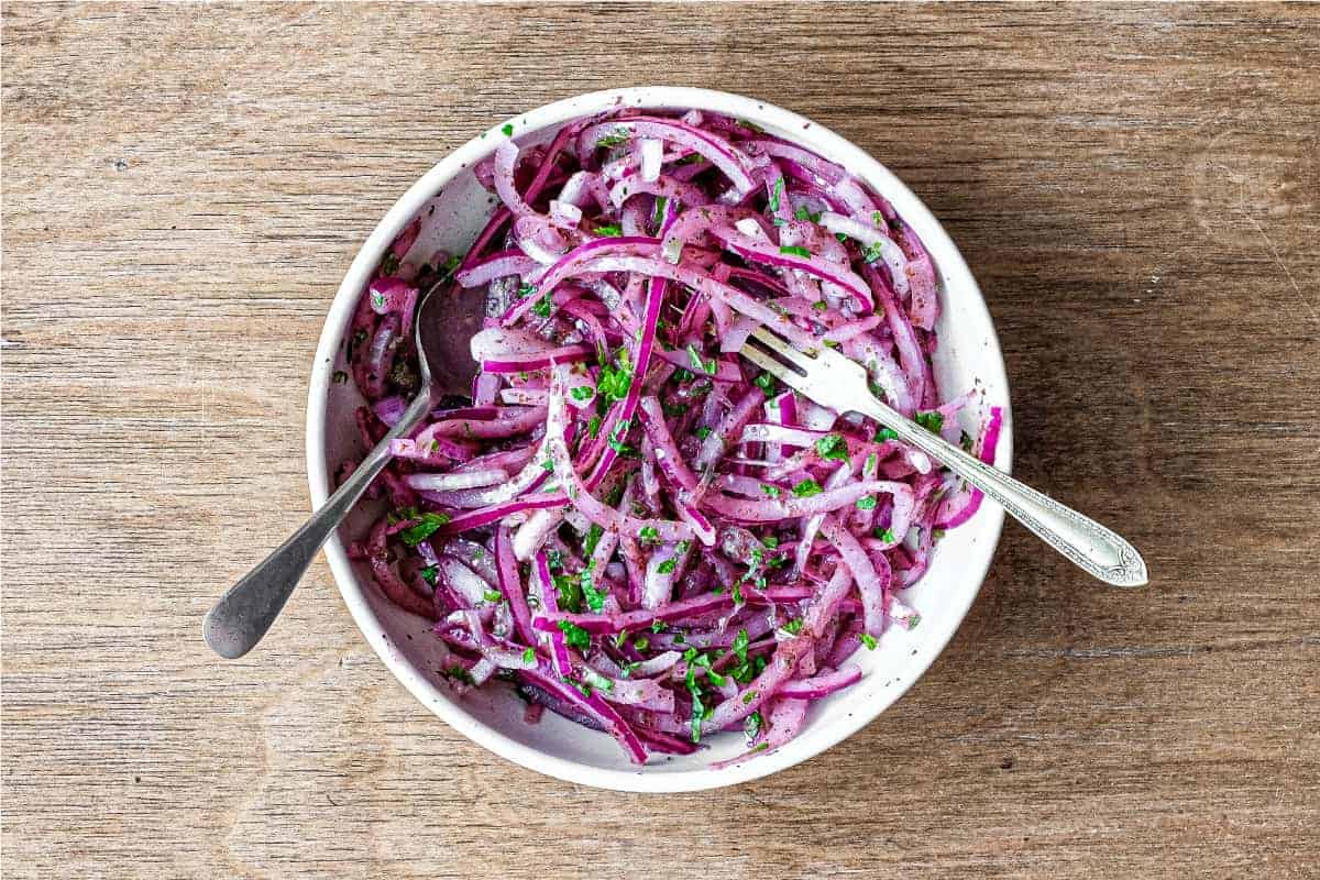 A small bowl of Sumac Onions with a small serving fork and spoon