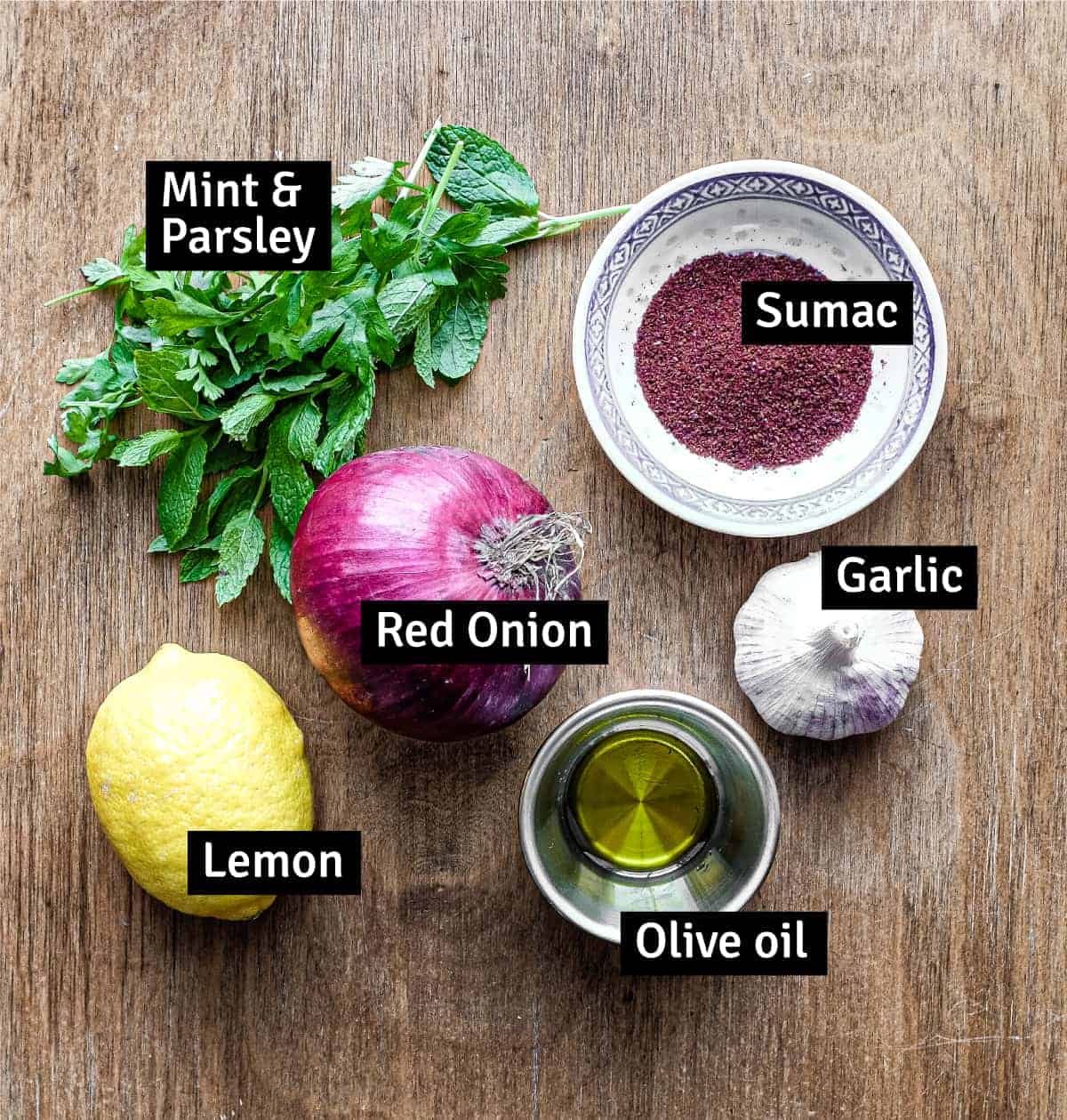 The ingredients for Sumac Onions: Red onion, sumac, garlic, lemon, olive oil, parsley and mint.