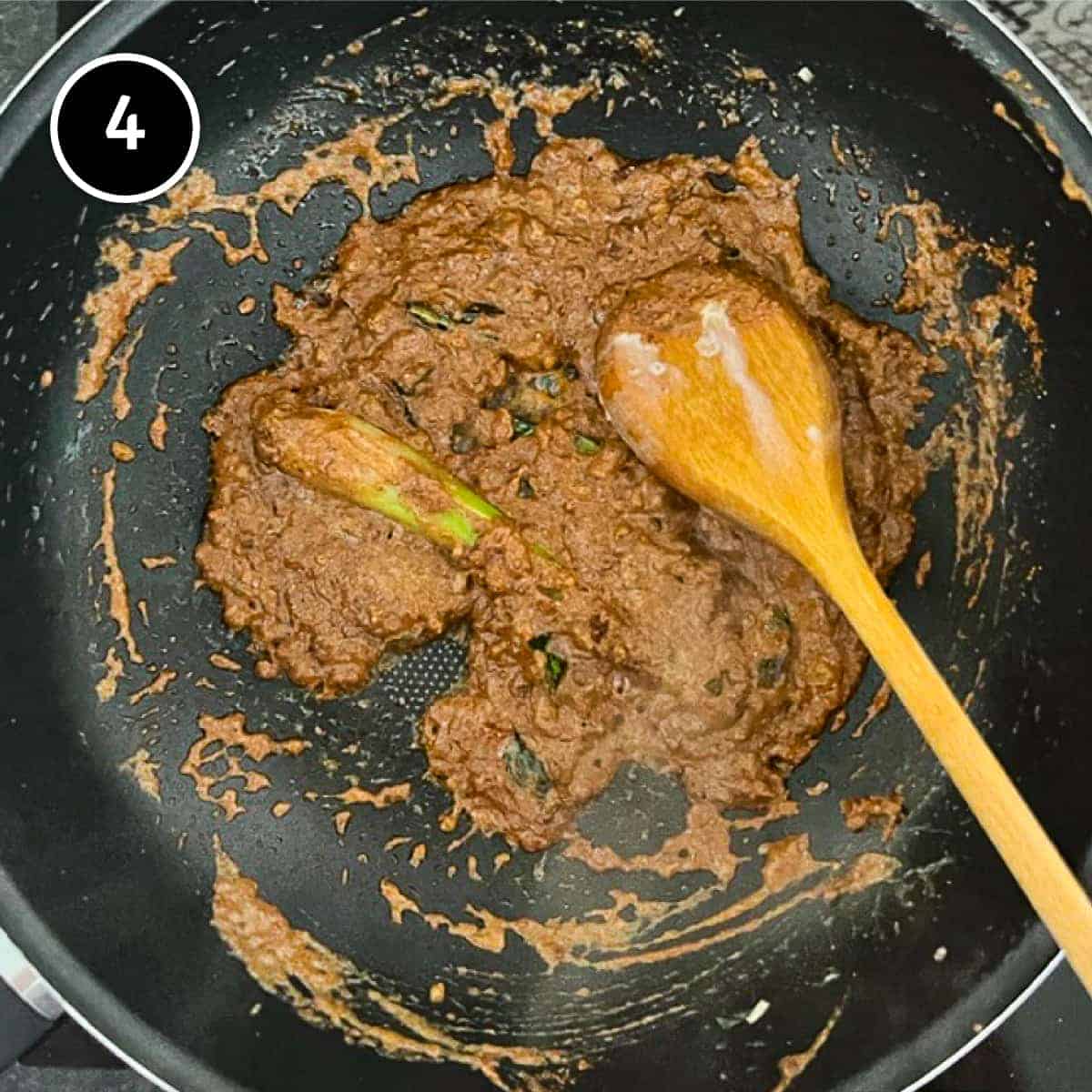 A curry spice mix is stirred in a pan with a wooden spoon