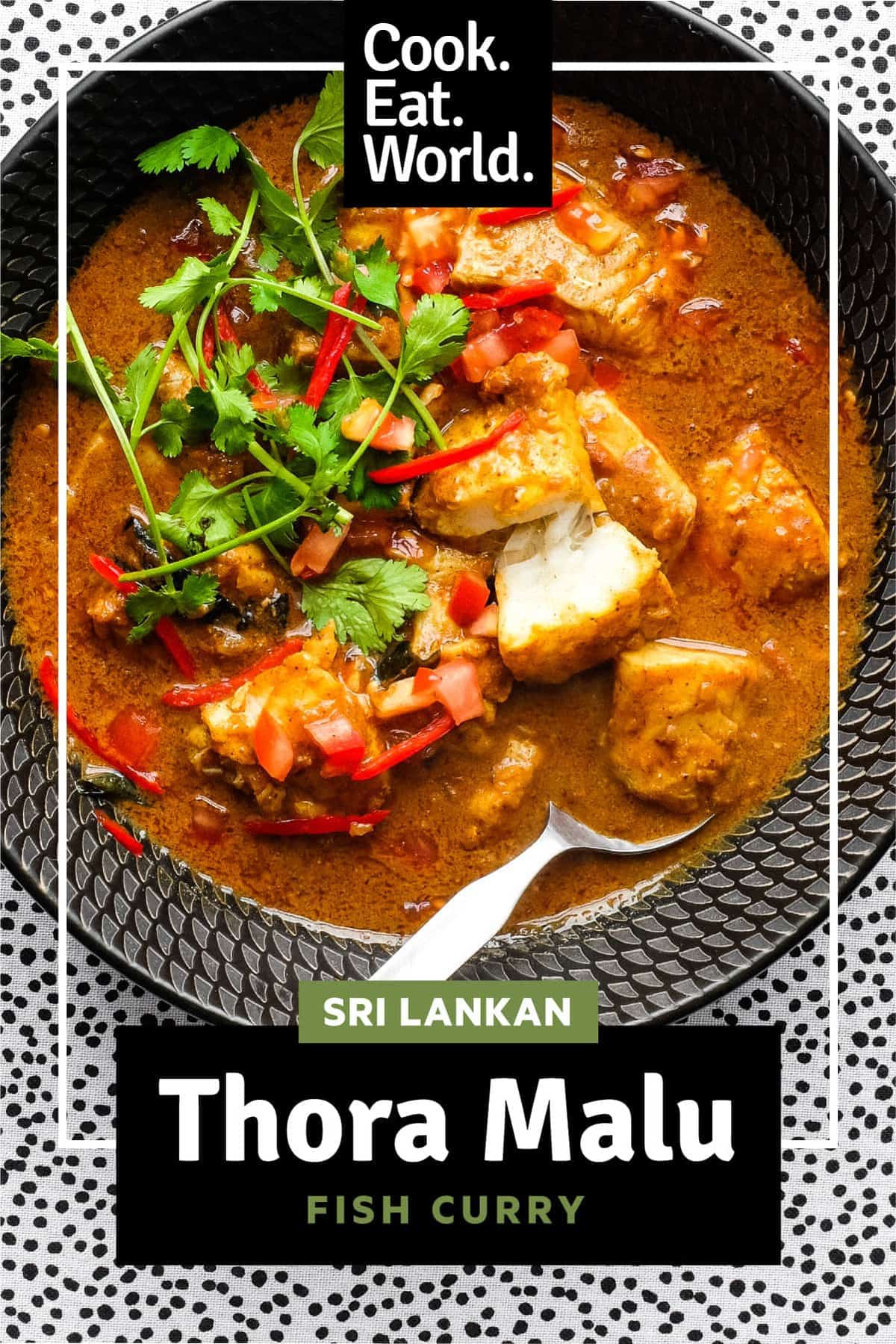 A bowl of Sri Lankan Fish Curry in a black bowl with a spoon, garnished with cilantro and red chilli.