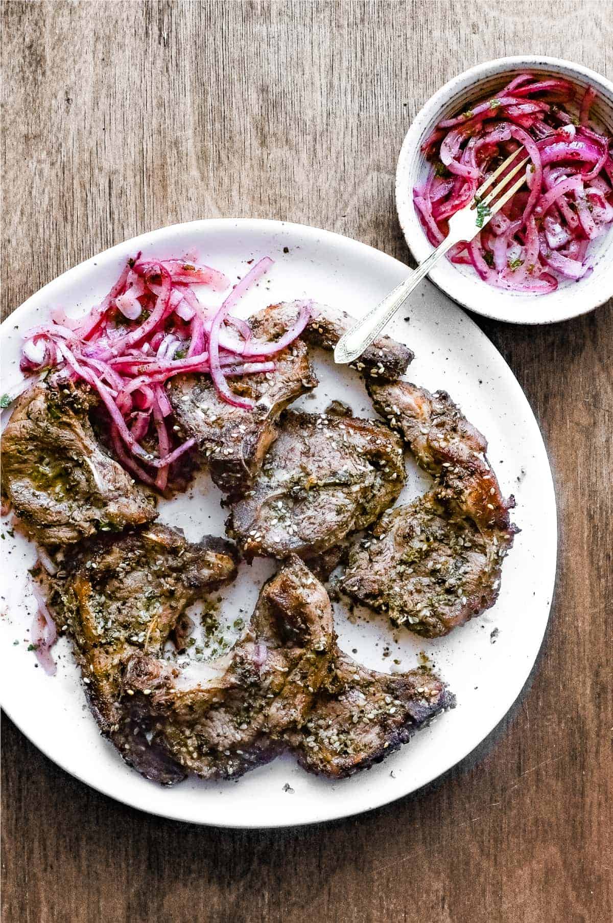 A platter of Zaatar Lamb chops with a side serving of Sumac Onion Salad