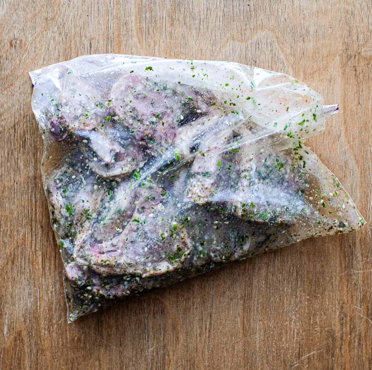 Lamb marinating in a large sealed plastic bag.