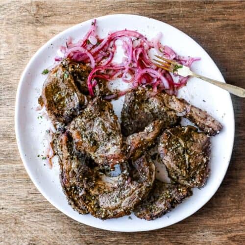 A platter of Zaatar Lamb chops with a side serving of Sumac Onion Salad