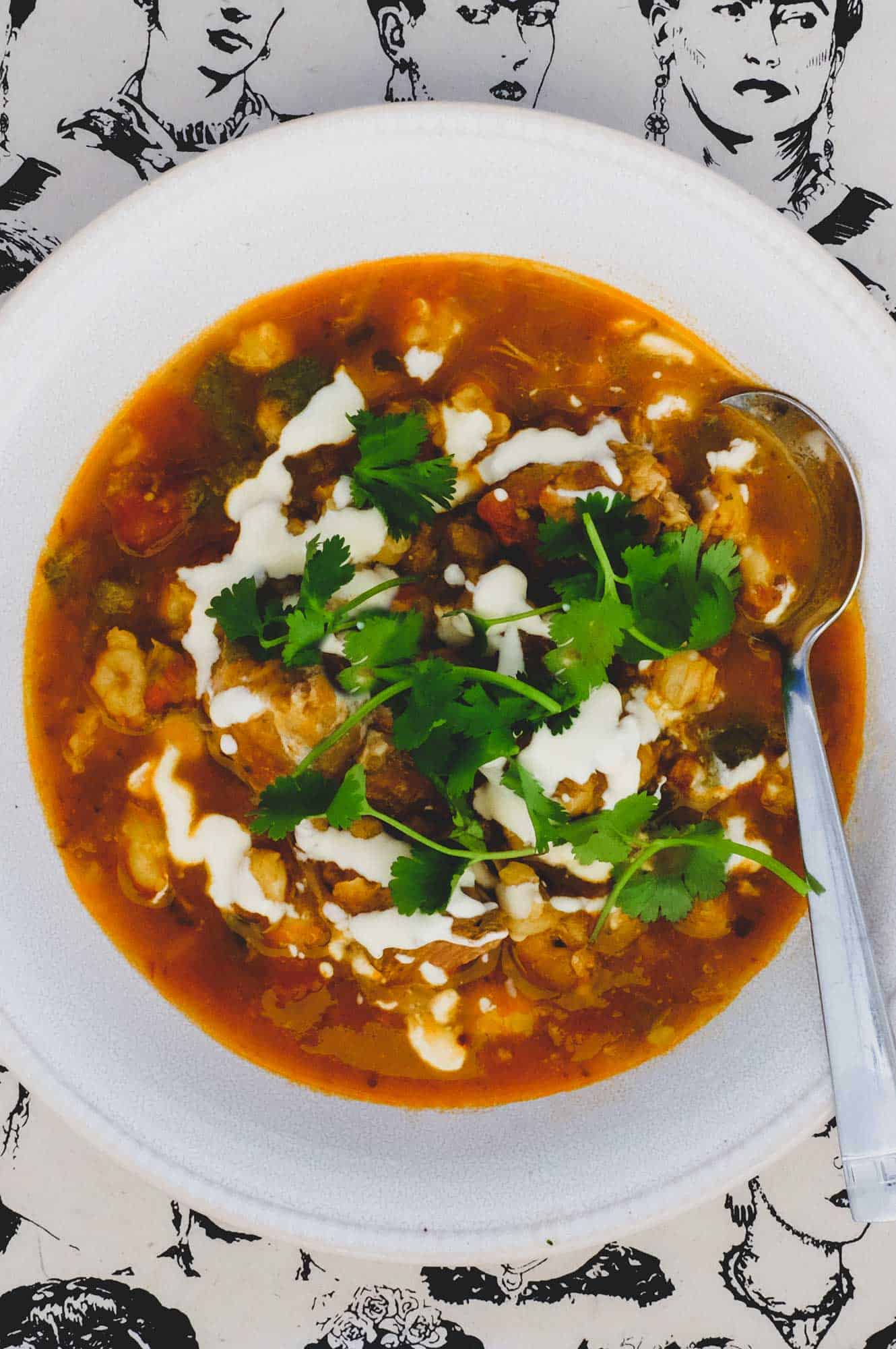 A bowl of Mexican Pozole Rojo on a background featuring sketches of Frida Kahlo