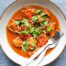 A bowl of Burmese chicken curry with fork and spoon