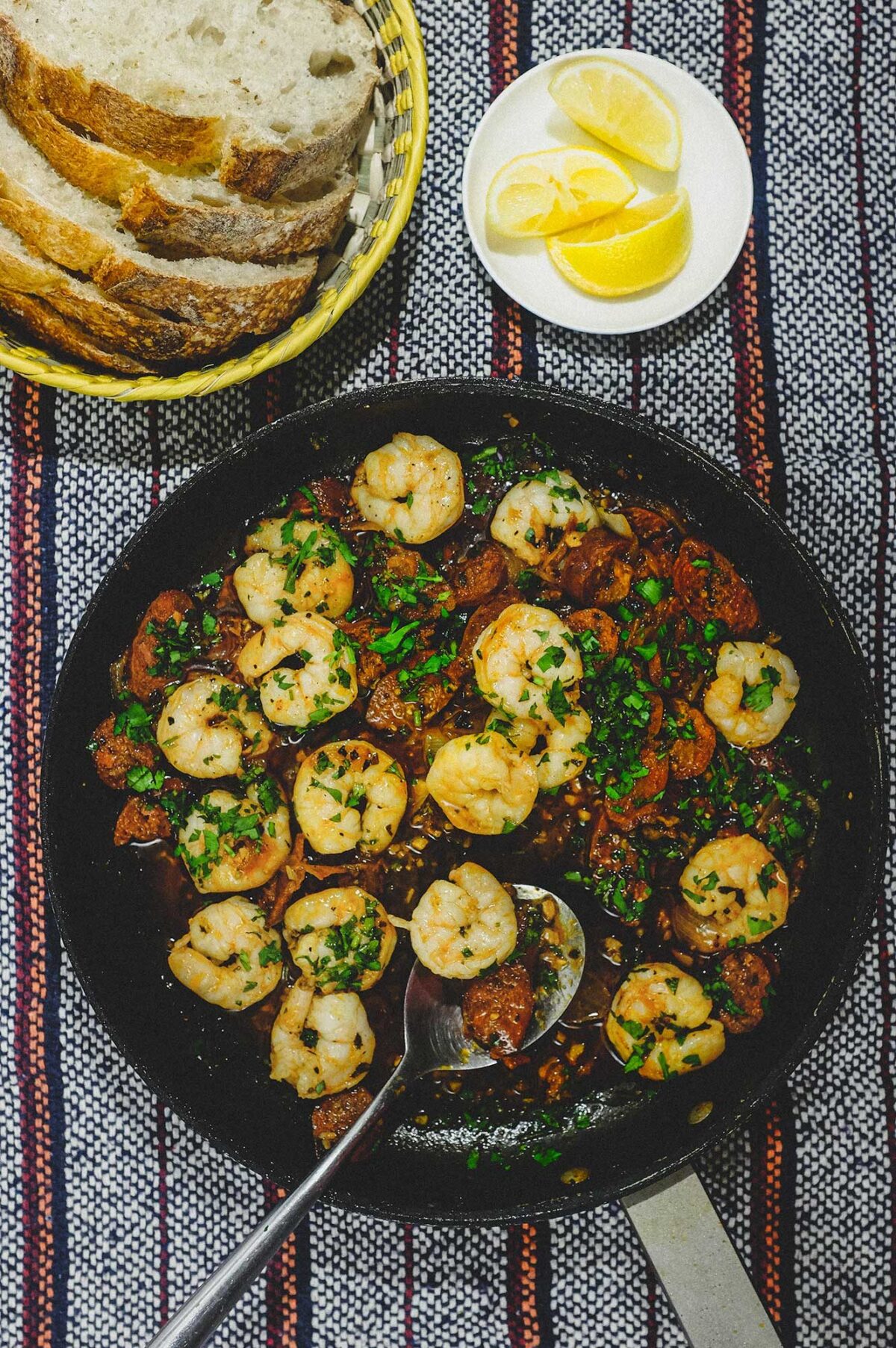 A platter of chorizo and prawns cooked in Fino Sherry. Bowls of lemon wedges and bread sit alongside.