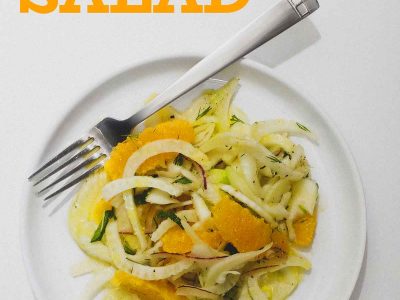 A plate of fennel & Orange Salad with a glass of white wine to the side.