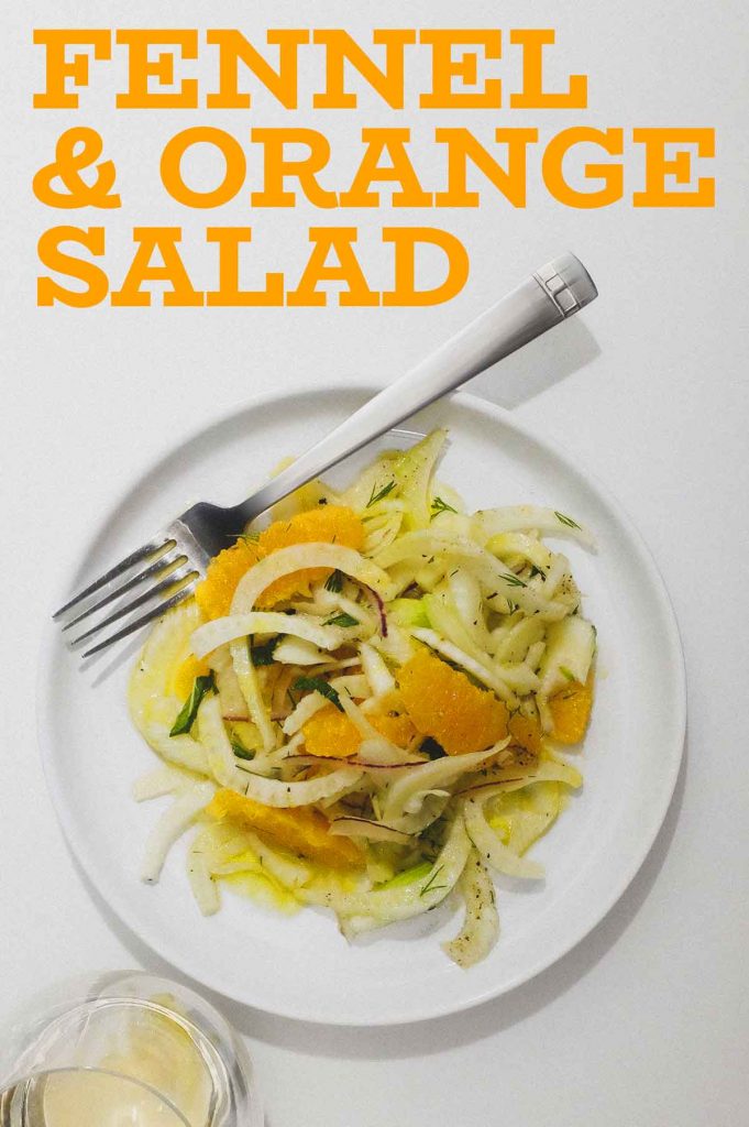 A plate of fennel & Orange Salad with a glass of white wine to the side.