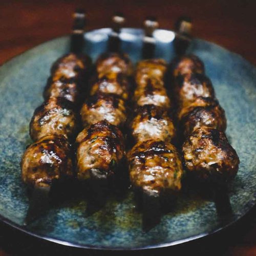 Cypriot sheftalia on metal skewers on a platter