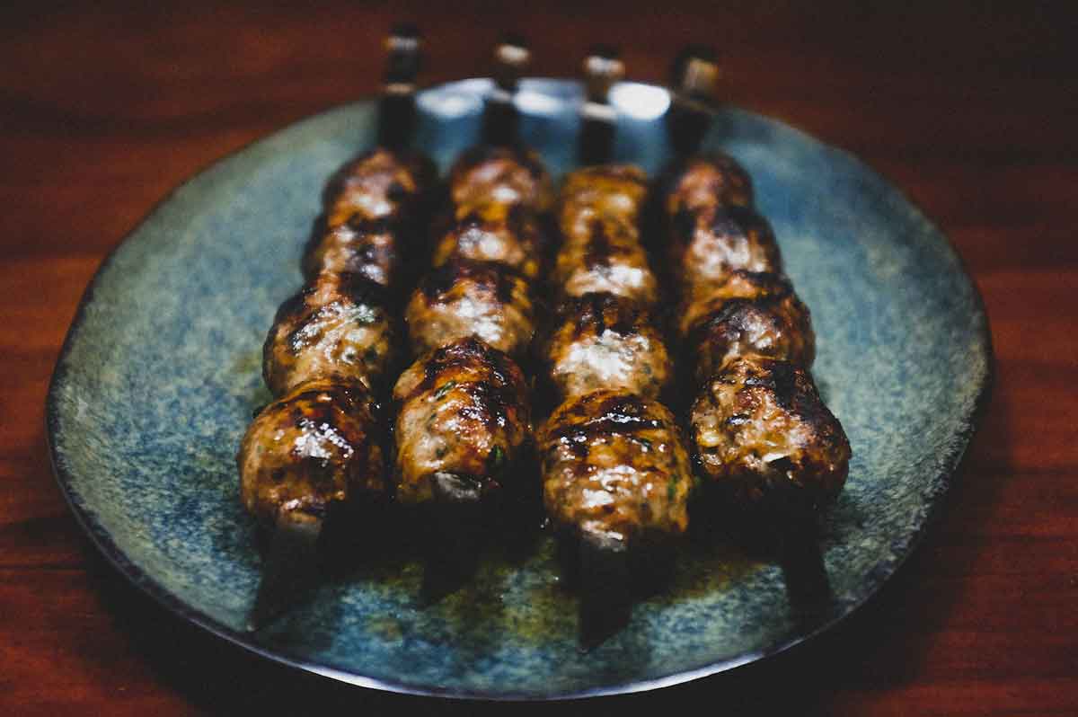 Cypriot sheftalia on metal skewers on a platter