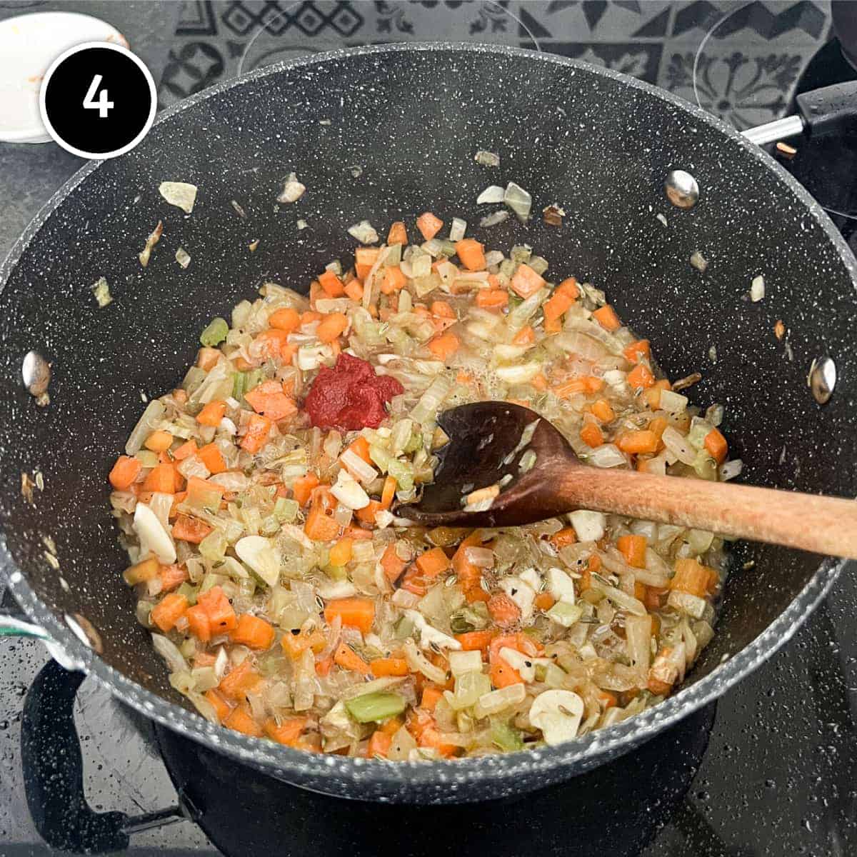 Onion, carrot and celery with tomato puree and white wine simmering in a pan