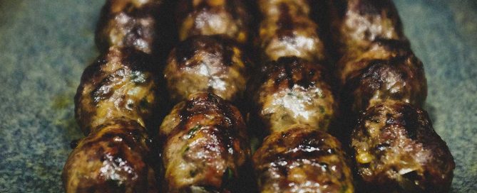 Cypriot sheftalia on metal skewers on a platter