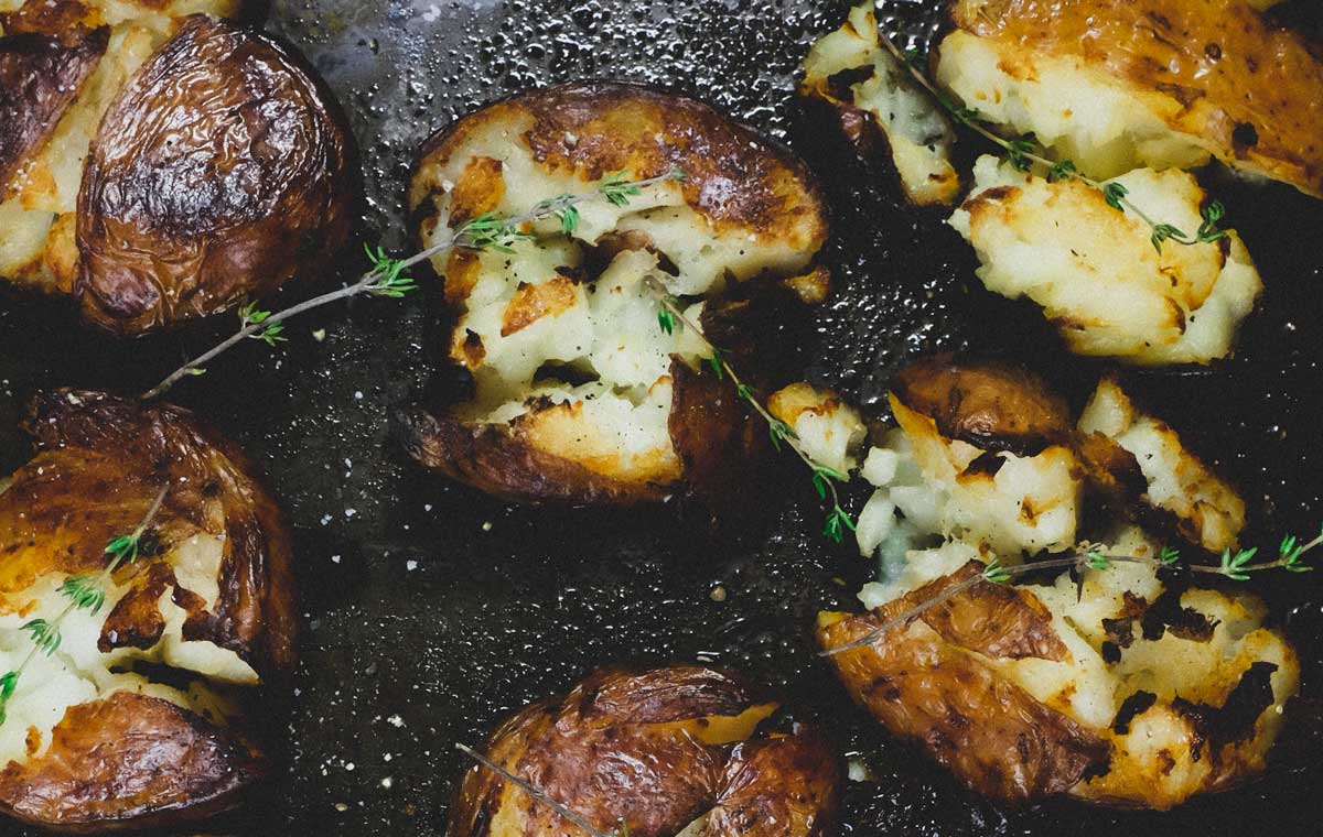 Punched potatoes on a baking sheet garnished with a little fresh thyme.