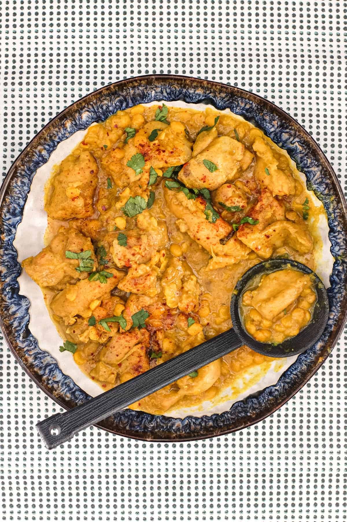 A plate of Pakistani Chicken Lahori curry with a black serving spoon