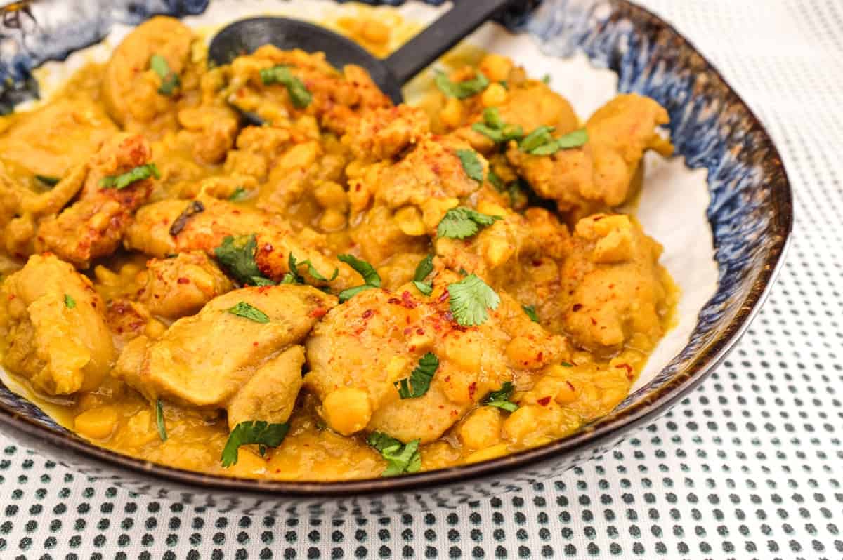 A plate of Pakistani Chicken Lahori curry with a black serving spoon