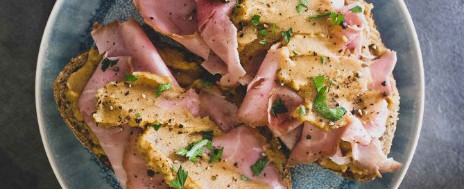 A an open sandwich with ham and pease pudding.