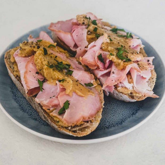 A an open sandwich with ham and pease pudding.
