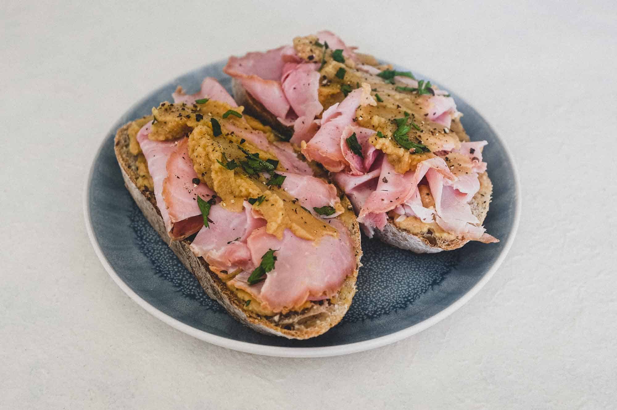 A an open sandwich with ham and pease pudding.