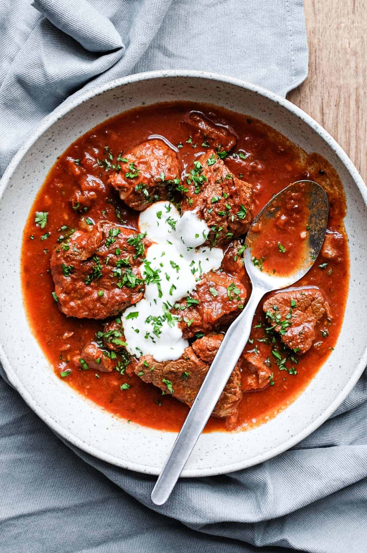 A bowl or Hungarian Pörkölt Beef Stew in a bowl, wrapped in a tea towel.