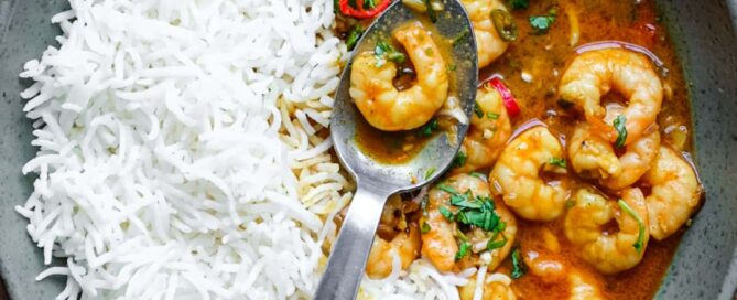 A bowl with Malai prawn curry and rice with a spoon