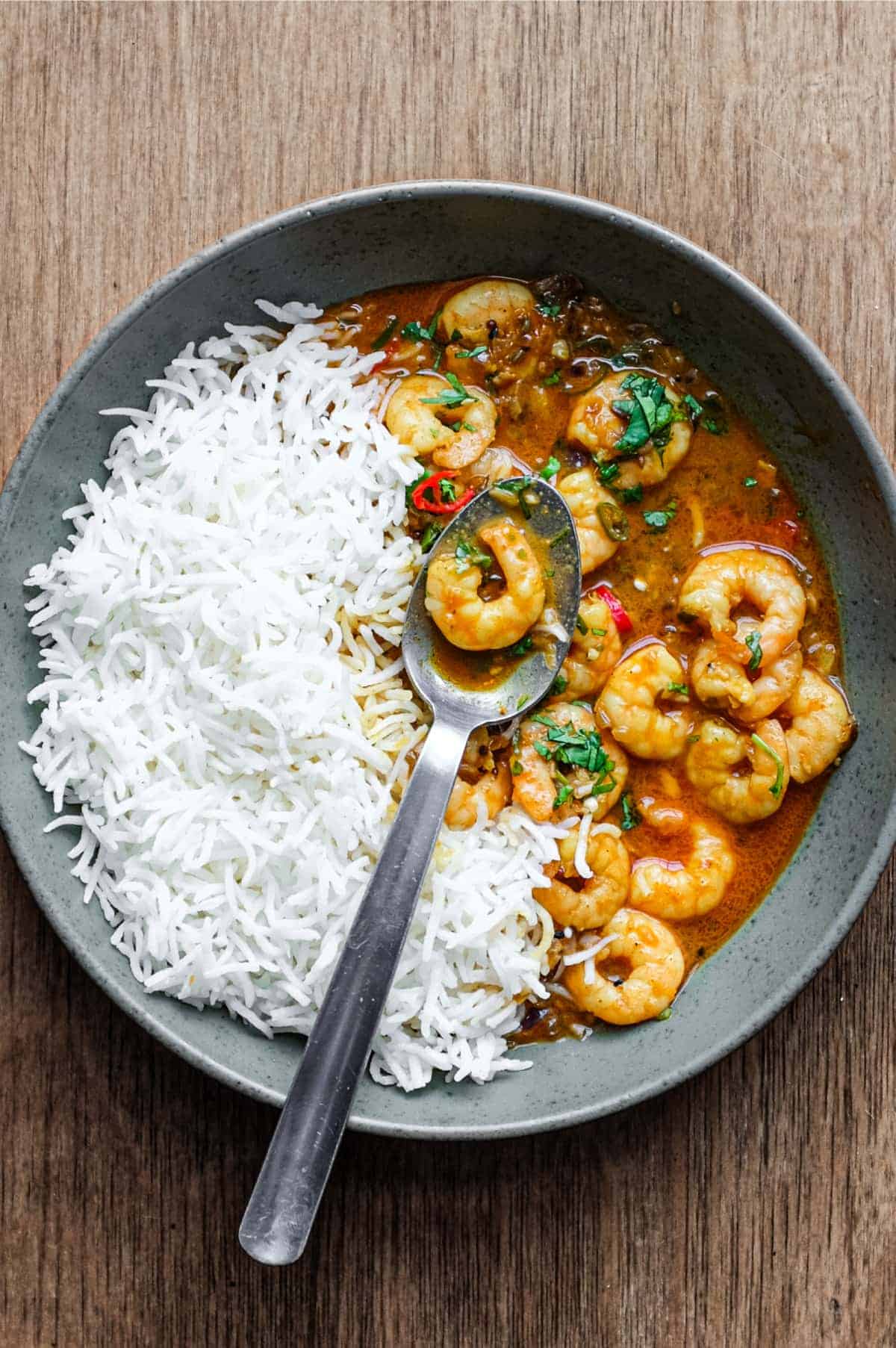 A bowl with Malai prawn curry and rice with a spoon