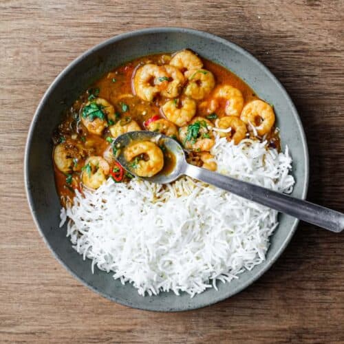 A bowl with Malai prawn curry and rice with a spoon