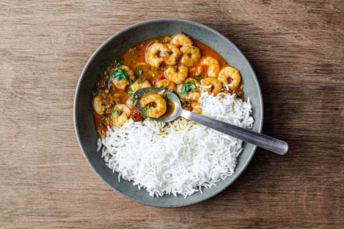 A bowl with Malai prawn curry and rice with a spoon