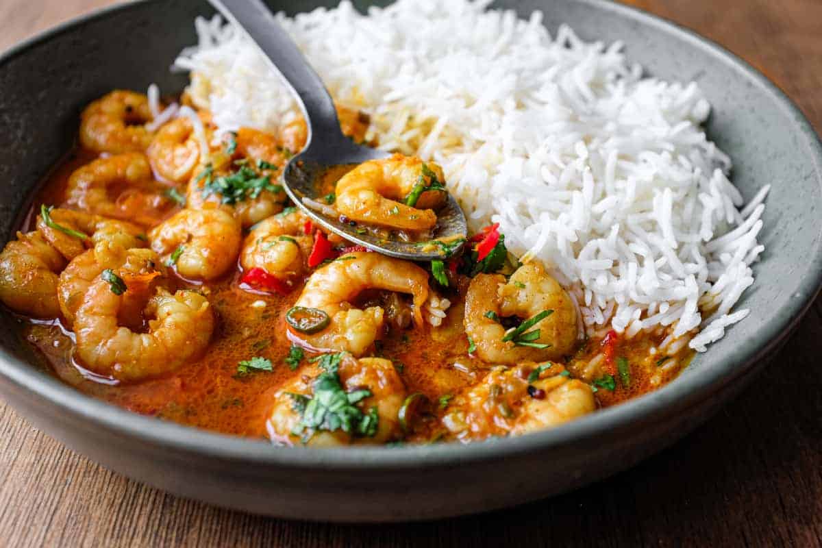 A bowl with Malai prawn curry and rice with a spoon