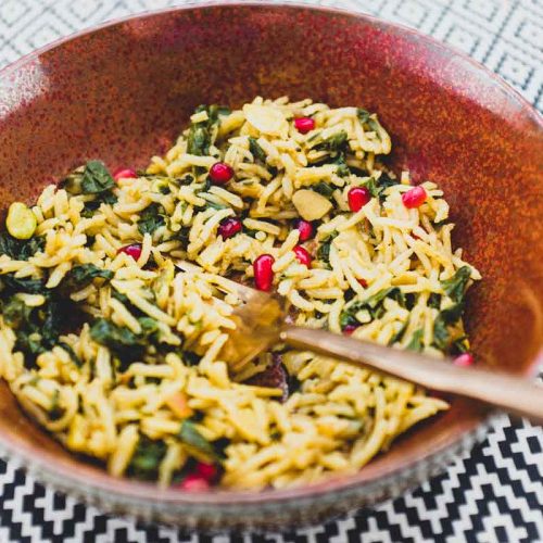 A small bowl holds some Moroccan rice with Silverbeet, garnished with pomegranate seeds