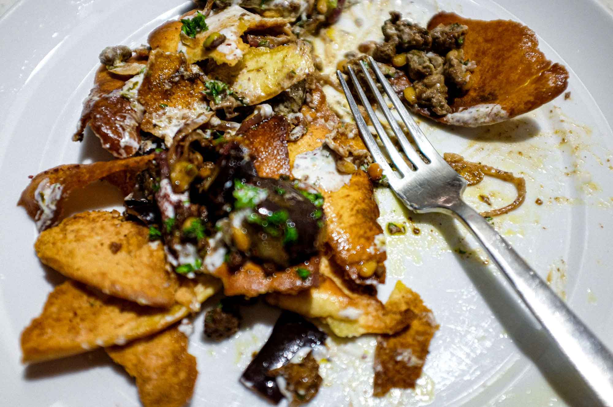 a platter of Lamb & Eggplant Fatteh garnished with fresh parsley and sumac