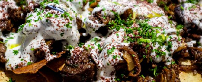a platter of Lamb & Eggplant Fatteh garnished with fresh parsley and sumac