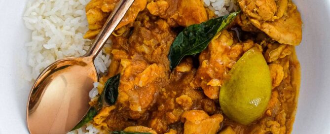 A bowl of Chicken Pathia Curry with chicken and limes with rice.
