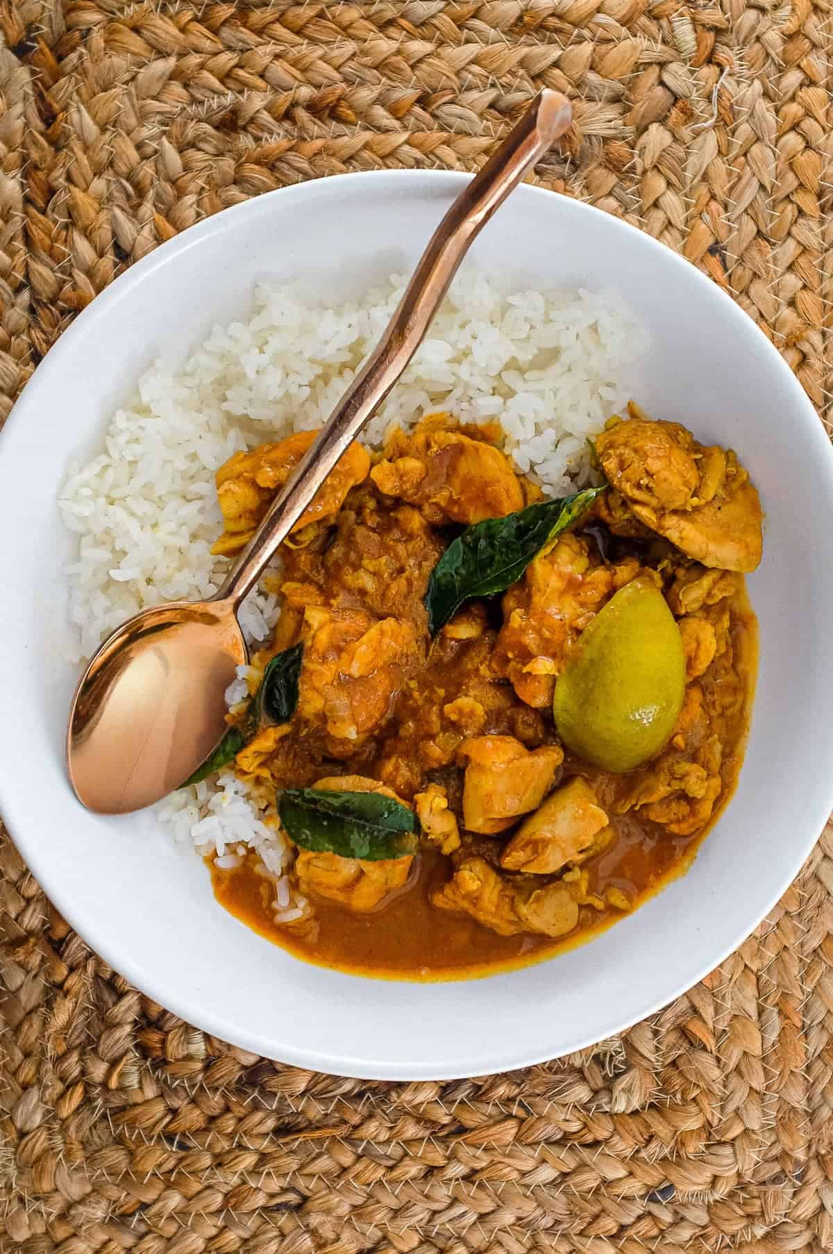 A bowl of Chicken Pathia Curry with chicken and limes with rice.